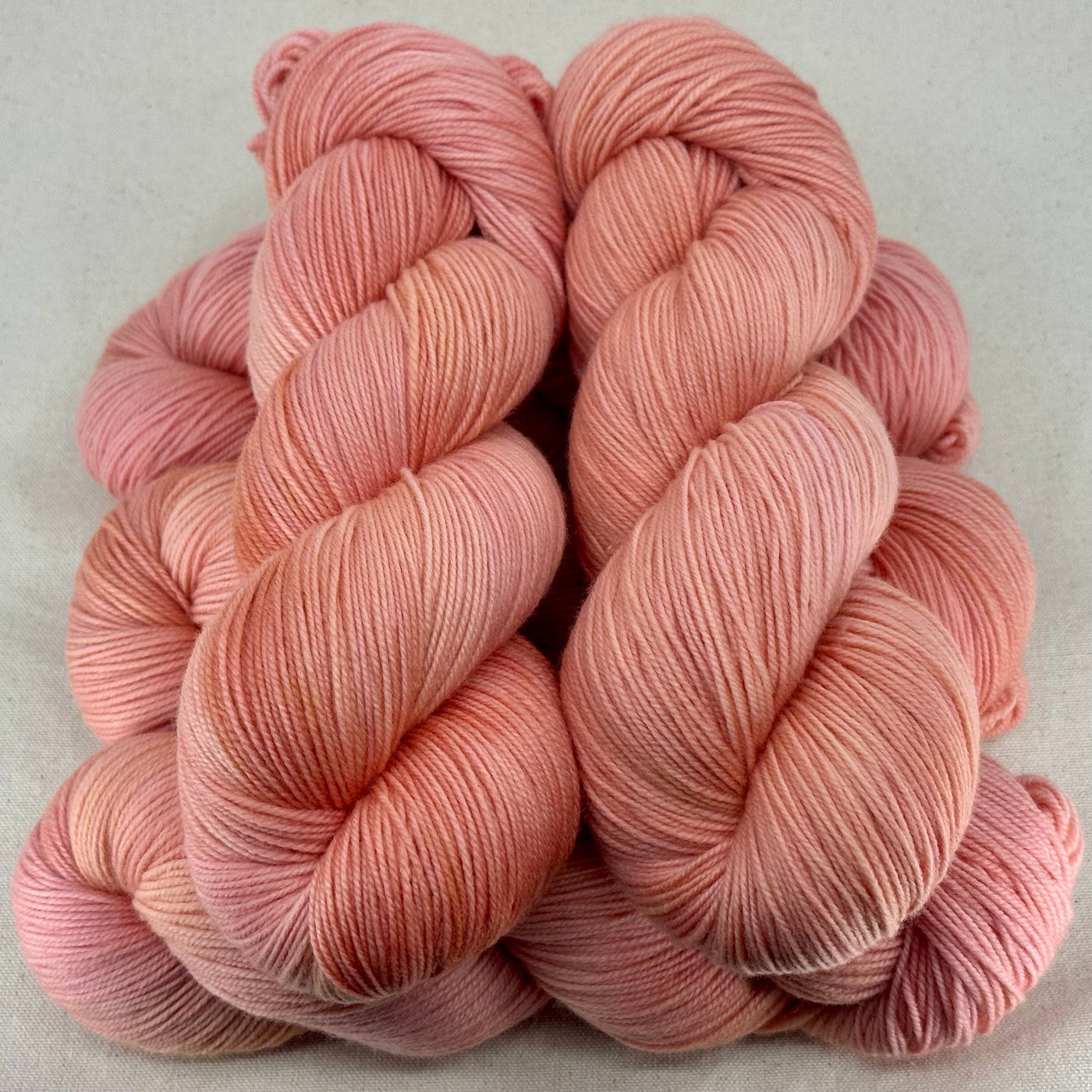 Three skeins of pink yarn on a light gray background