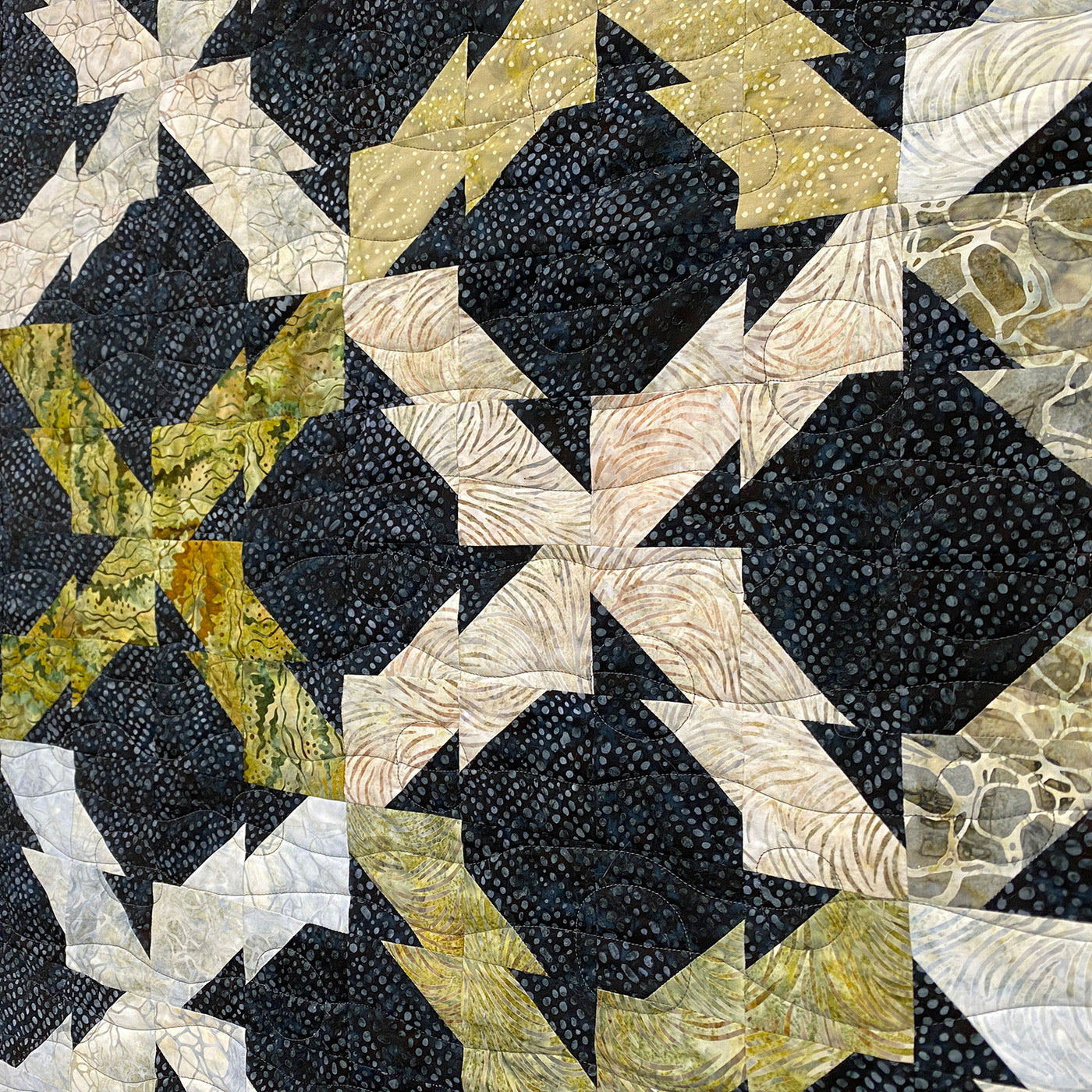 Quilt with geometric pattern in black, white, and gold on a dark background
