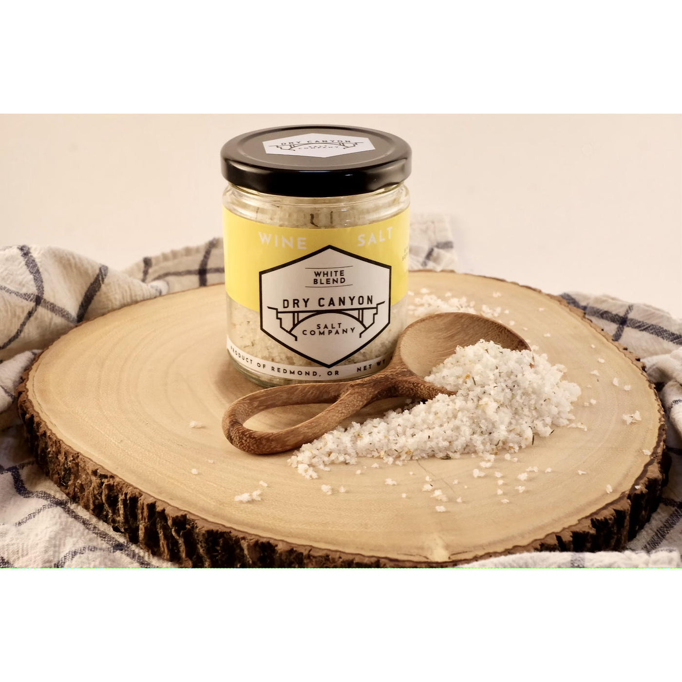 Jar of White Canyon Salt on a wooden board with a wooden spoon