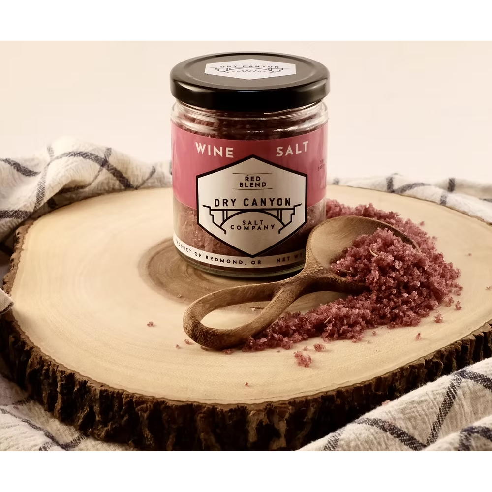 Jar of wine salt from Dry Canyon Salt Company on a wooden board with a spoonful of salt.